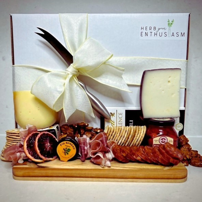 A wooden board filled with an array of meats, cheeses, crackers, fruits, and nuts.